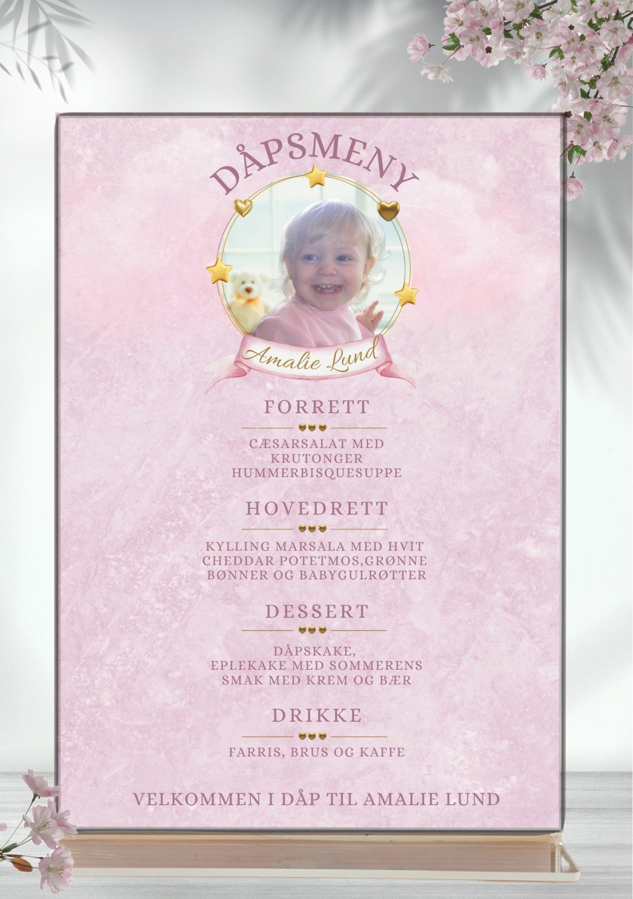 Personlig dåpsmeny med foto, gullstjerner og lyserosa bakgrunn – elegant menydesign med forrett, hovedrett og dessert fra KISS DEKOR