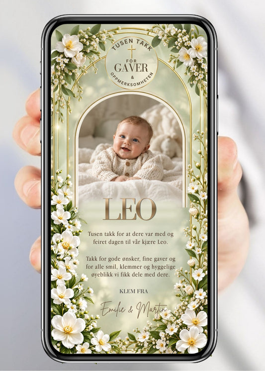 Digitalt takkekort til dåp og navnefest med babyfoto i bueformet gullramme, hvite blomster og gypsophila rundt hele kortet, kors-logo øverst, barnets navn i gullhåndskrift og "Klem fra" med foreldrenes navn på sageblå/mintgrønn bakgrunn